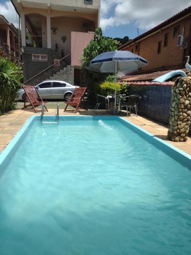 a large blue swimming pool with an umbrella and chairs at Pousada Oca Porã in Conservatória