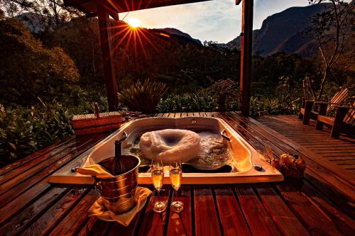 a bath tub on a wooden deck with the sun setting at Refúgio Ecológico Pedra Afiada in Praia Grande