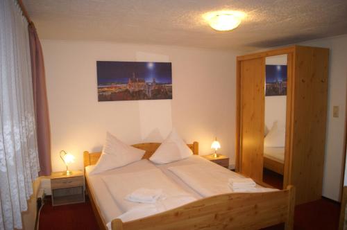 ein Schlafzimmer mit einem Bett mit zwei Lampen und einem Spiegel in der Unterkunft Pension Zur Sonne in Mansfeld