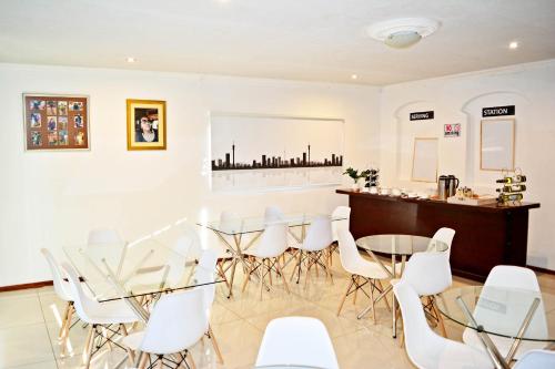 a dining room with a table and white chairs at MaU Bed and Breakfast in Krugersdorp