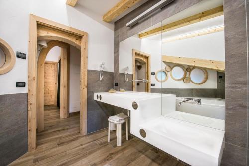 ein Badezimmer mit einem großen weißen Waschbecken und einer Badewanne in der Unterkunft Chalet Pineta relax location in Canazei
