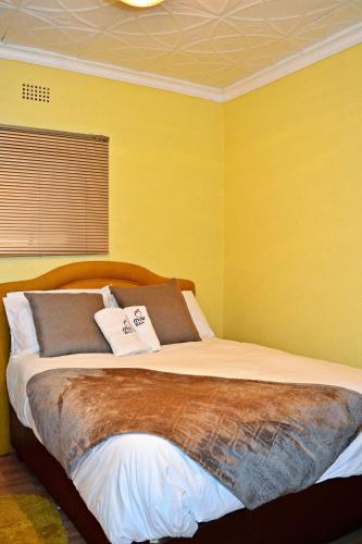 a bedroom with a large bed with yellow walls at MaU Bed and Breakfast in Krugersdorp
