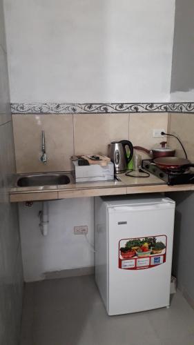 a small kitchen with a sink and a small refrigerator at Habitacion Vacacional Camboriu in Salinas