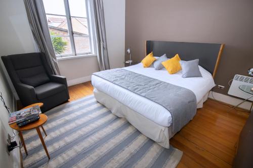 a bedroom with a king sized bed and a chair at New Voga Hotel Boutique in Valparaíso
