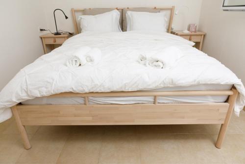 een groot bed met witte lakens en witte kussens bij הגורן in Kefar Szold