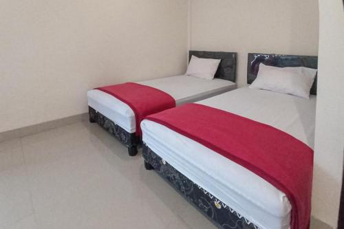 two beds sitting next to each other in a room at RedDoorz Syariah near Sentani City Square in Weversdorp