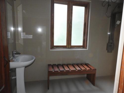 a bathroom with a sink and a window and a bench at Wilpattu Tree House in Wilpattu