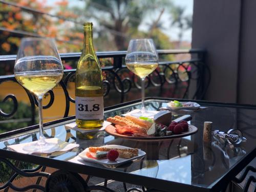 een glazen tafel met twee glazen wijn en eten bij Casa del Sol Inn in Ajijic