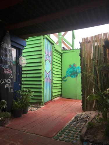 a green building with a painting on the side of it at Green House Hostel in Cabo Polonio