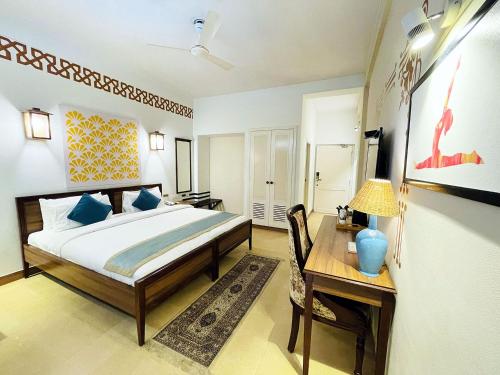 a bedroom with a bed and a table and a desk at Yog Niketan By Sanskriti in Rishīkesh