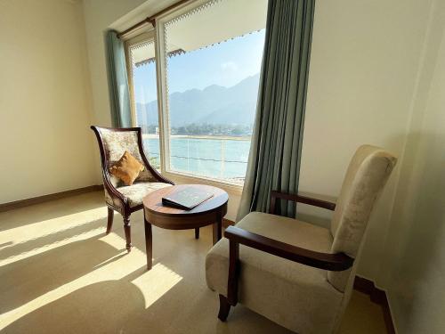a room with a chair and a table and a window at Yog Niketan By Sanskriti in Rishīkesh
