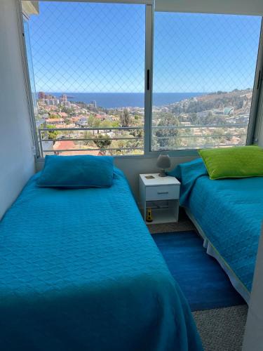 two beds in a room with a large window at Edificio En Reñaca in Viña del Mar