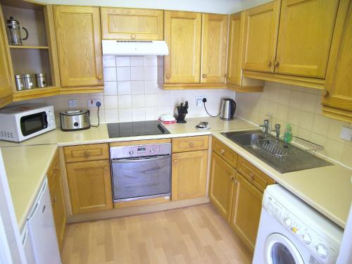 a kitchen with wooden cabinets and a sink and a microwave at Royal Mile, Edinburgh - 2 Bedroom Apartment in Edinburgh