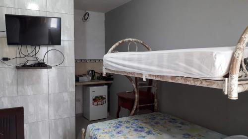 1 dormitorio con litera y TV en la pared en Habitacion Vacacional Camboriu, en Salinas