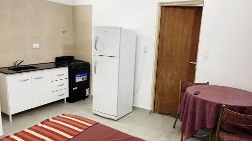 a kitchen with a white refrigerator and a table at Santa Teresita Apartments by San Remo in Santa Teresita