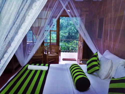 Un dormitorio con una cama grande con almohadas verdes y blancas en Ella Green Cottages en Ella