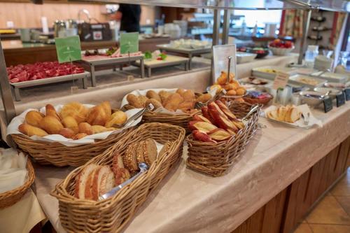 a buffet line with baskets of bread and pastries at Flair Hotel Sonnenhof in Baiersbronn