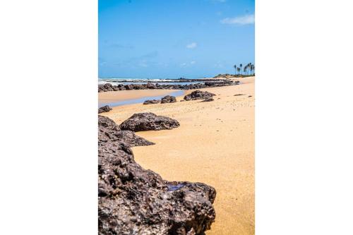 a beach with rocks on the sand and the ocean at Qavi - Leuchtturm House #ParaisoDoBrasil in Parnamirim