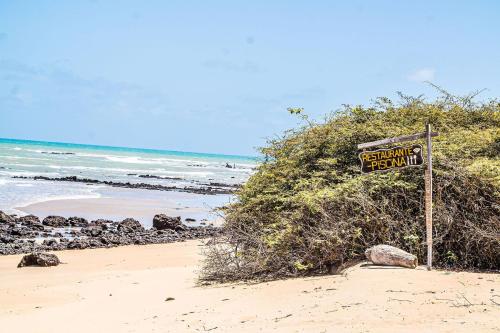 a sign on a beach next to the ocean at Qavi - Leuchtturm House #ParaisoDoBrasil in Parnamirim
