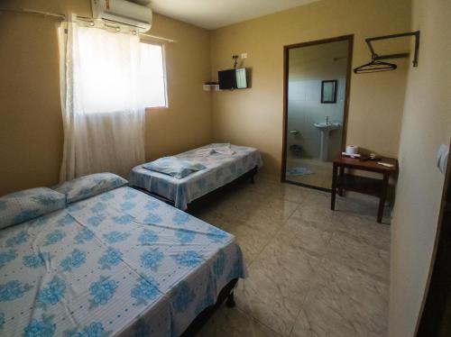 Habitación con 2 camas y baño con espejo. en Casa Morada da Praia 2, en Peroba