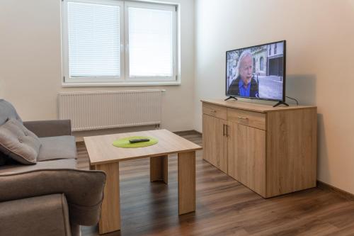 a living room with a flat screen tv on a wooden cabinet at Apartmány SKI KRASLICE - NOVĚ OTEVŘENO in Kraslice