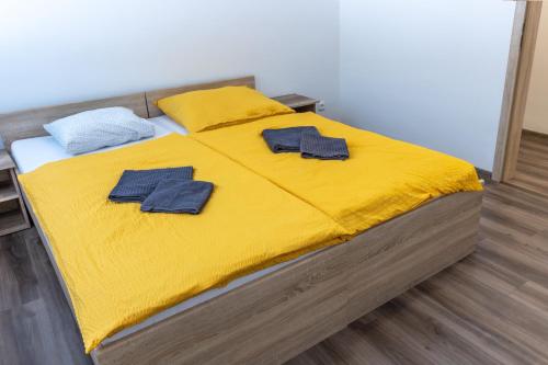 a bed with yellow sheets and blue pillows on it at Apartmány SKI KRASLICE - NOVĚ OTEVŘENO in Kraslice