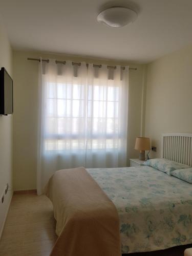 a bedroom with a bed and a large window at Apartments Sol de Almeria Golf y Playa II in Almería
