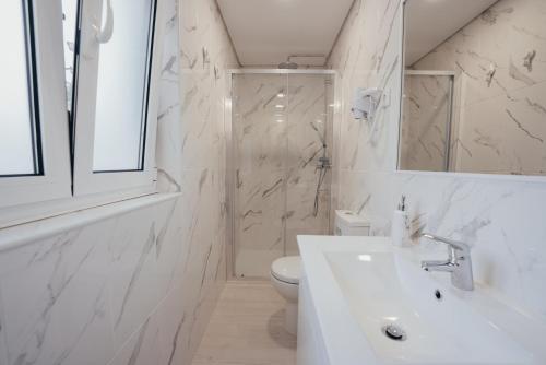 La salle de bains blanche est pourvue d'un lavabo et de toilettes. dans l'établissement Cabanelas Country House - Casa do Luís, à Vale de Cambra