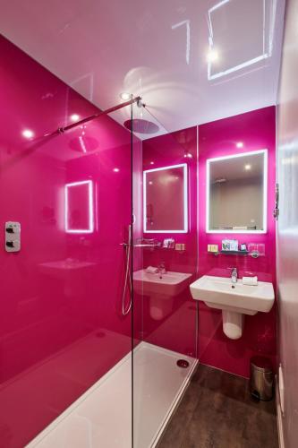 a pink bathroom with two sinks and a shower at The Parklands Hotel in Perth