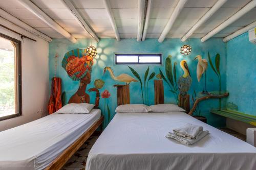 two beds in a room with a painting on the wall at Mar Amar Cabaña - Hostel in Coveñas