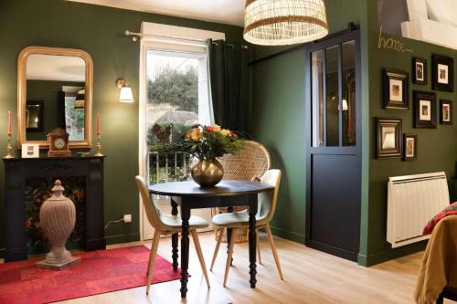 a dining room with green walls and a table and chairs at Les Patis in Vouvray