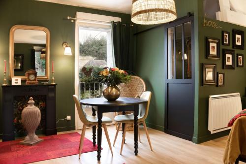 une salle à manger avec des murs verts, une table et des chaises dans l'établissement Les Patis, à Vouvray