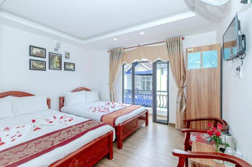 a hotel room with two beds and a balcony at Moc Nhien Hostel Da Lat in Da Lat