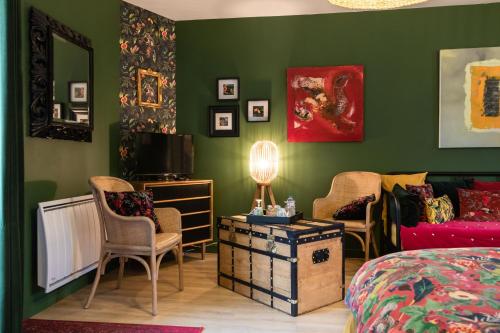 a bedroom with green walls and a bed and chairs at Les Patis in Vouvray