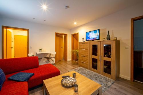 ein Wohnzimmer mit einem roten Sofa und einem TV in der Unterkunft Bördeapartment 1 in Vahldorf