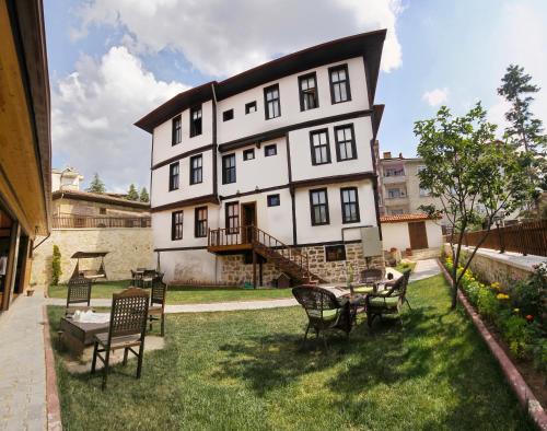 a large white house with chairs and a table in the yard at Kadıoğlu Konağı in Kastamonu