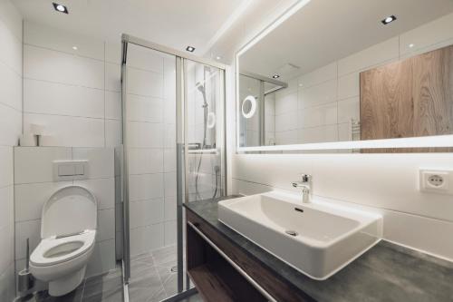 a white bathroom with a sink and a toilet at Alpenheim Apartment Ischgl in Ischgl