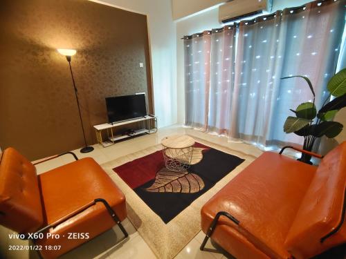 a living room with two orange chairs and a television at PavilionVillie Ipoh in Kampong Sengat