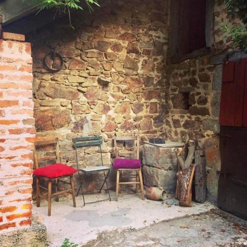 a group of chairs sitting next to a stone wall at Combrailleurs Gite in Espinasse