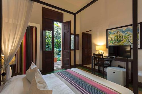 a bedroom with a bed and a desk with a television at Hotel Villa Colonial in Santo Domingo
