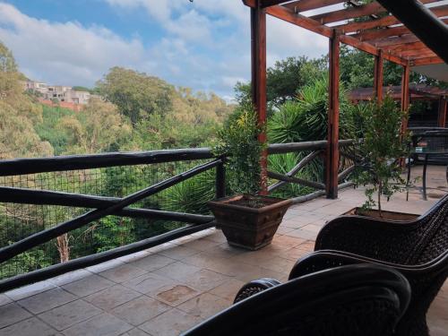 a balcony with chairs and a view of trees at Coral Tree Inn in Pretoria