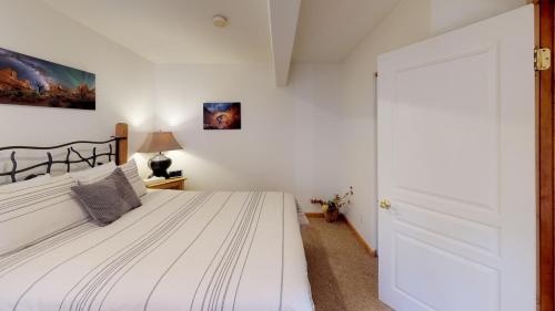a bedroom with a white bed and a door at Arena Roja #2279 in Moab