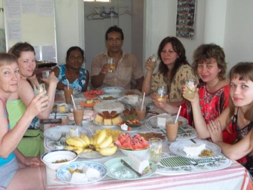 a group of people sitting around a table eating food at Anura Home Stay in Kalutara