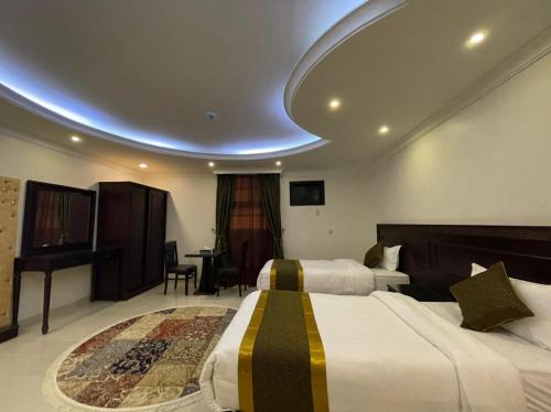 um quarto de hotel com duas camas e uma mesa em Arrawiya Alzahabia Hotel em Dammam