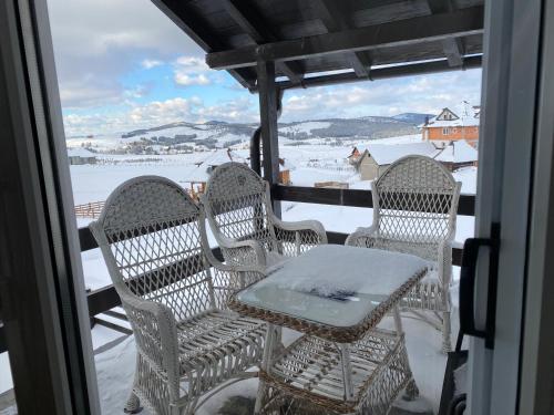 a table and chairs on a balcony with a view of snow at Vila Jela Tornik in Zlatibor