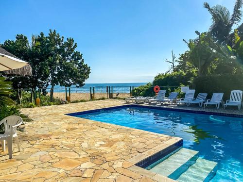 a swimming pool with chairs and the ocean in the background at O Costão do Sol in Balneário Camboriú
