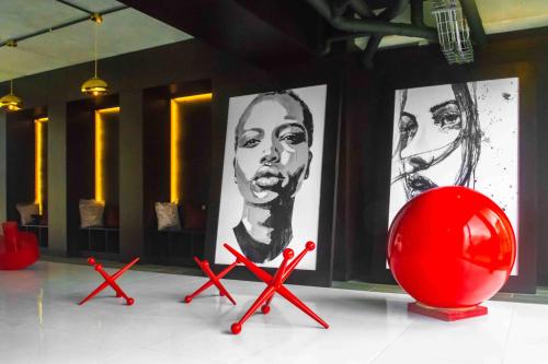 危地馬拉的住宿－Cayala Nuevo y Moderno Apto Shift Zona 16, cerca de Embajada de EEUU，一张红色椅子,放在一个贴有海报的房间