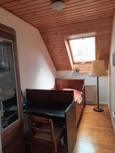 a bedroom with a bed and a desk and a window at Wohnen beim Uswatta Liyanage in Troisdorf