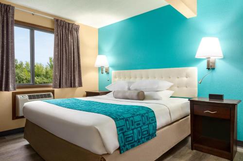 a bedroom with a large bed with a blue wall at Howard Johnson by Wyndham Waterloo/Cedar Falls in Waterloo