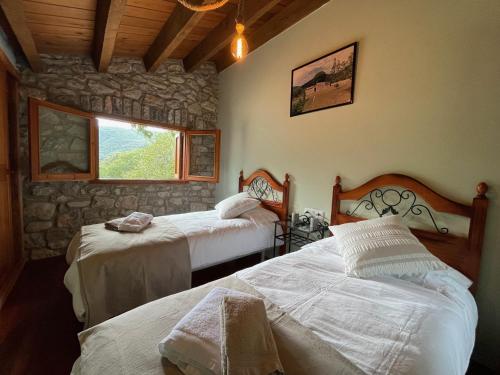 Un dormitorio con dos camas y una pared de piedra. en El Vilarot. La casa de piedra en la naturaleza., en Girona
